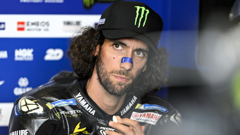 Alex Rins taxi ride: Alex Rins in a MotoGP paddock/garage portrait wearing Yamaha race gear and cap