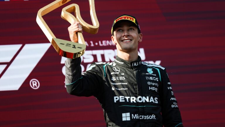 George Russell 2027 F1 tyres: George Russell holding a trophy on the podium in Mercedes gear.