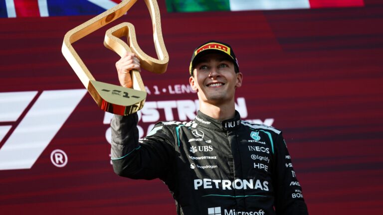 George Russell holding a trophy on the podium.