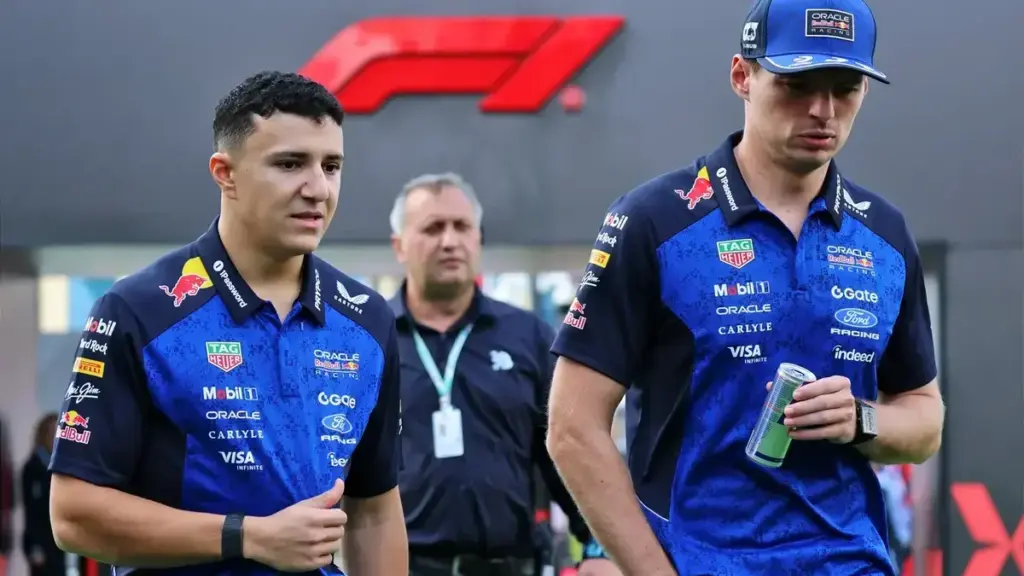 Verstappen software bug: Max Verstappen walking in the paddock alongside another Red Bull driver/teammate, with Red Bull/F1 branding visible in the background.