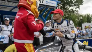 IndyCar record viewership: Alex Palou celebrating at an IndyCar event with a mascot.